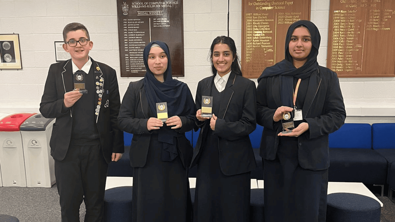 Laurus Ryecroft student Oliver and 3 students from Eden Girls' Leadership Academy stand holding medals achieved in the North West STEM Challenge January 2024 at the University of Manchester.